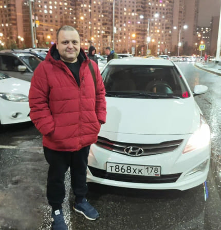 Фотография - Человек в красной пуховике рядом с белым автомобилем Hyundai на заснеженной улице