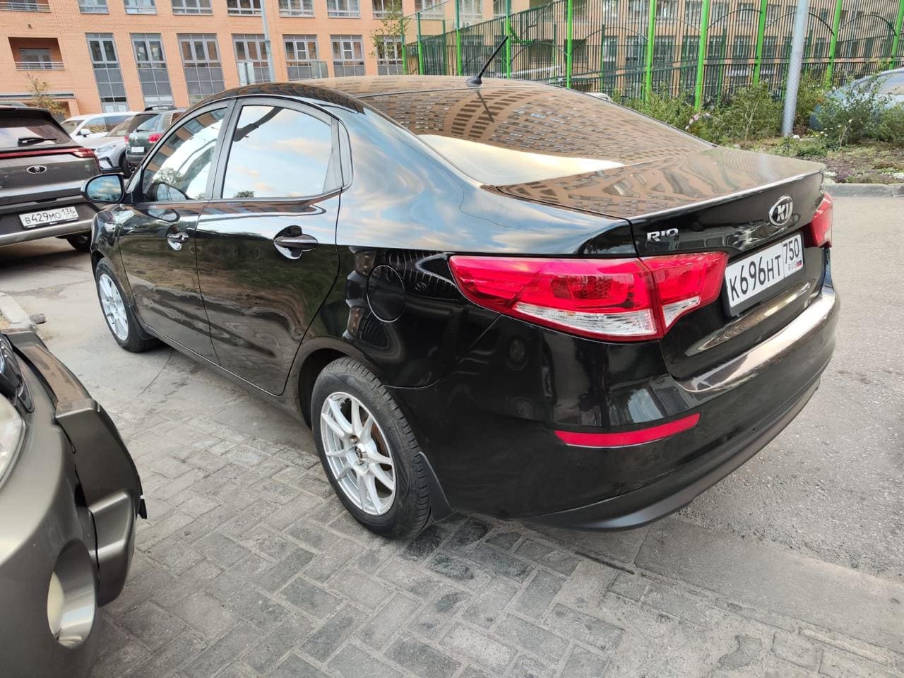 Фотография - Черный автомобиль Kia Rio на парковке возле жилого здания