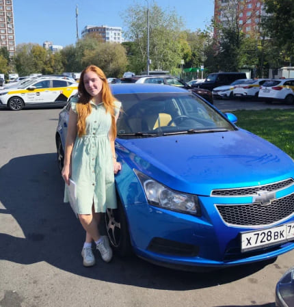 Фотография - Девушка рядом с синим автомобилем на парковке